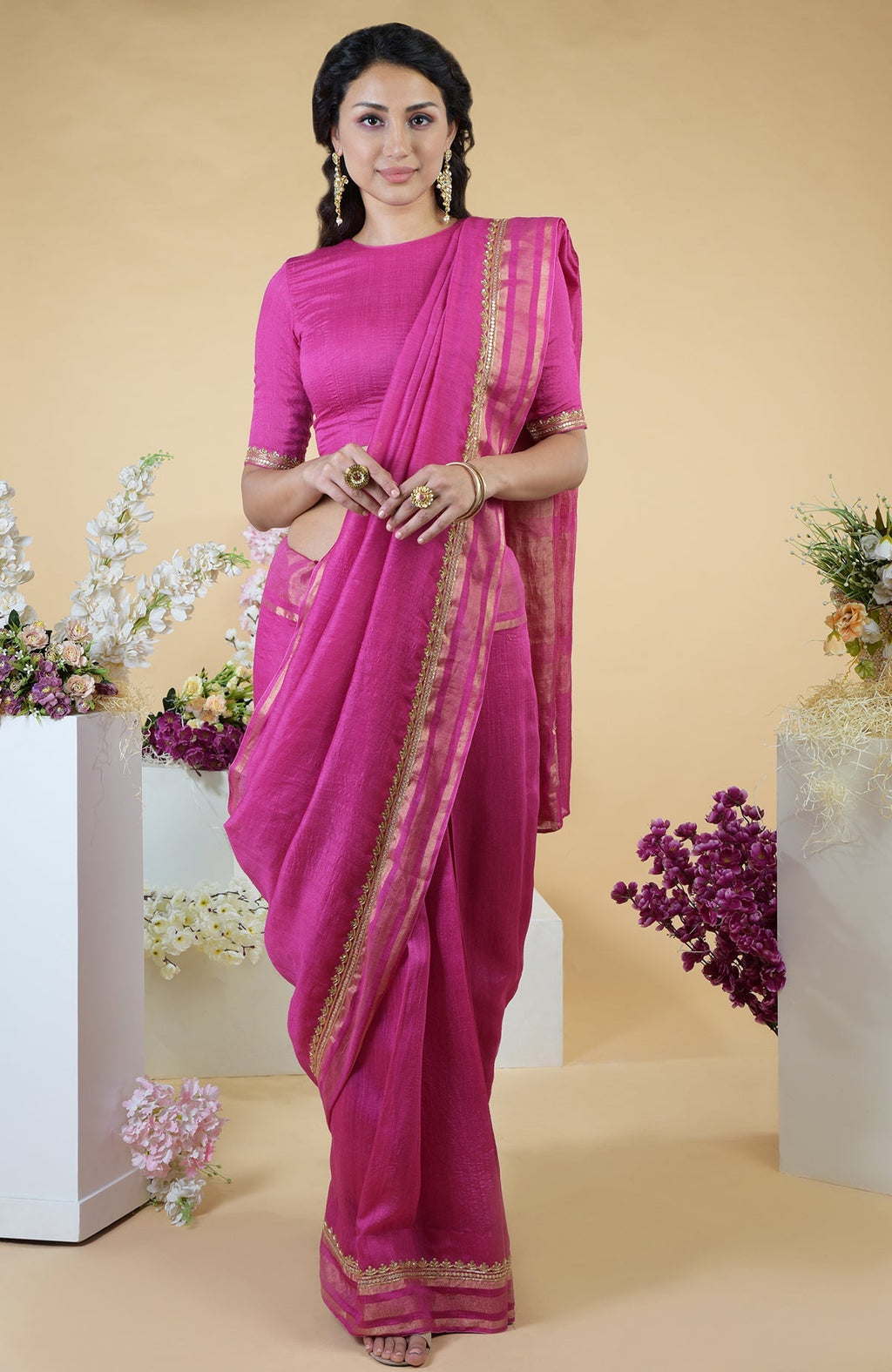 A woman models a raspberry linen saree with gold zardozi embroidery.