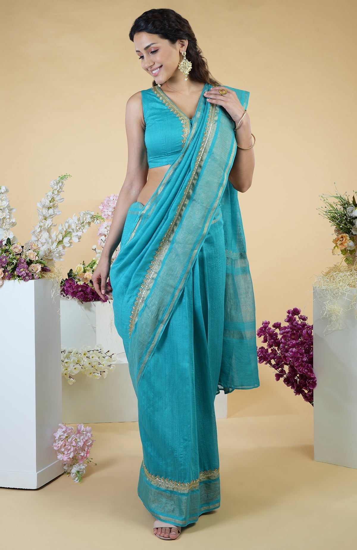 Teal blue hand-embroidered linen saree with a matching sleeveless blouse.