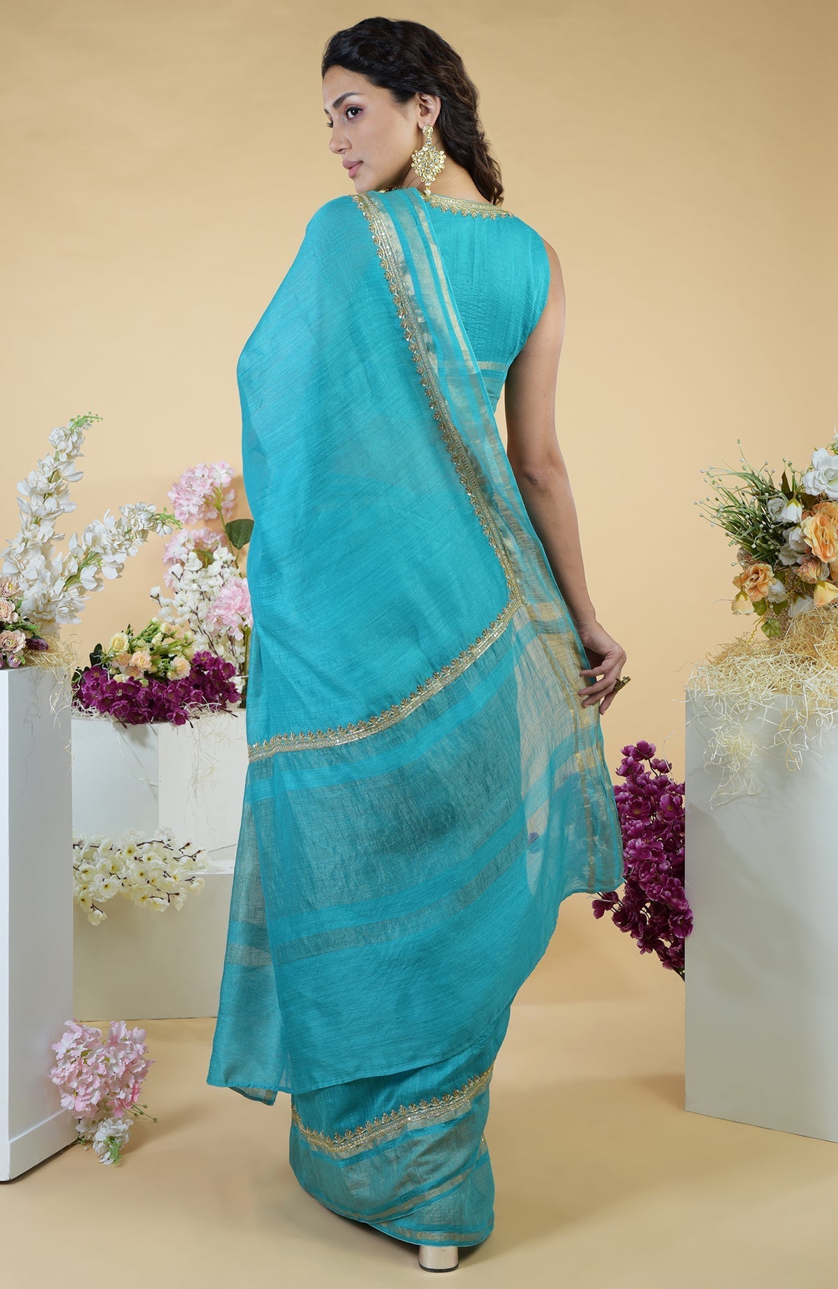 Teal blue linen saree with gold zardozi embroidery and a matching sleeveless blouse.