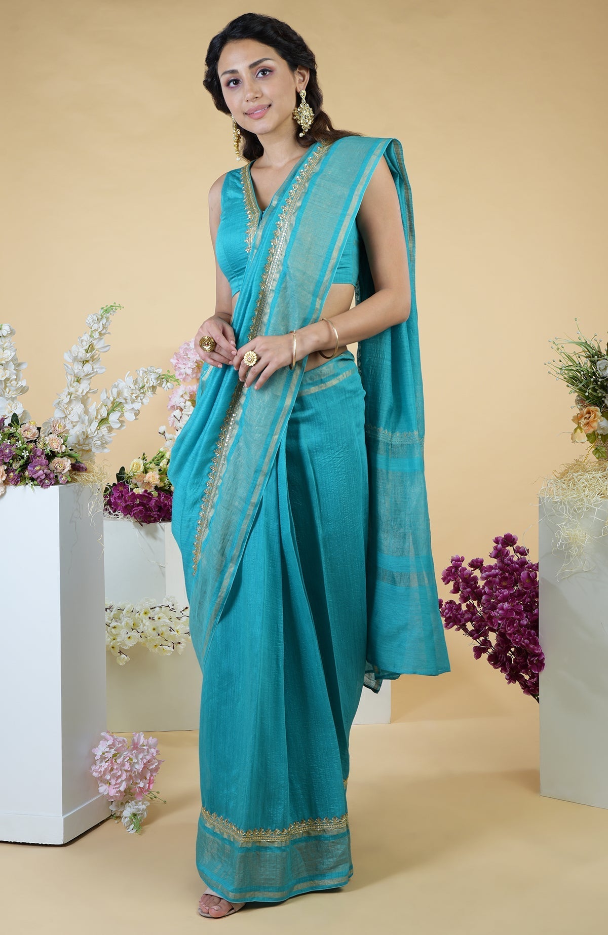 Teal blue hand-embroidered linen saree with a matching sleeveless blouse.