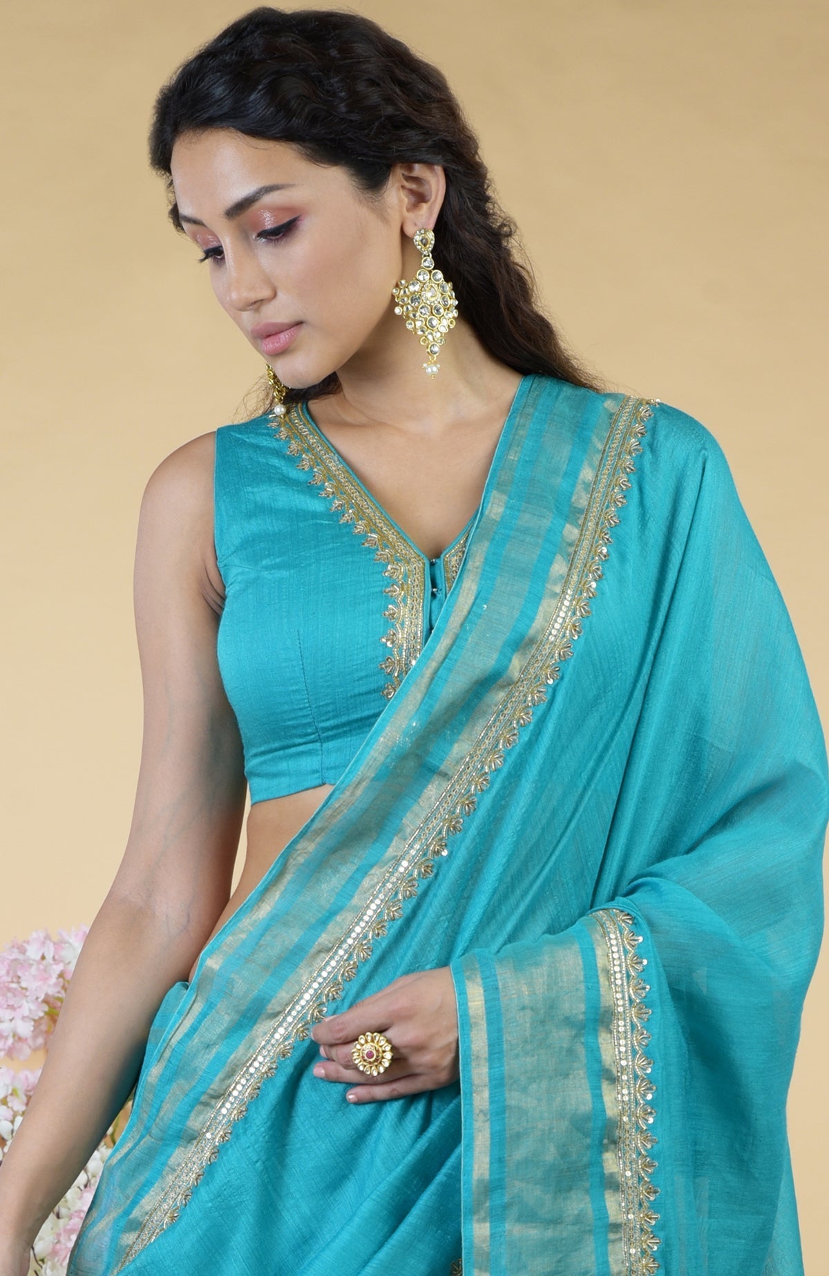 Teal blue linen saree with gold hand embroidery and a matching sleeveless blouse.