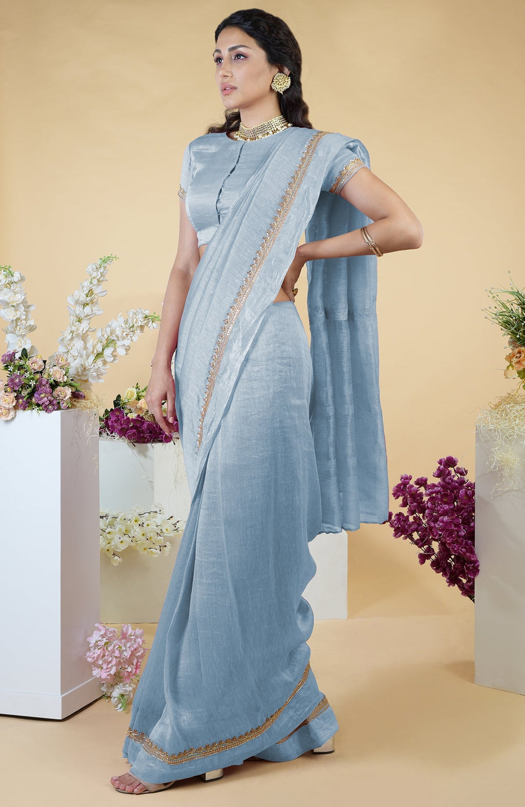 Dusty blue linen saree with hand-embroidered gold zardozi border and matching blouse.