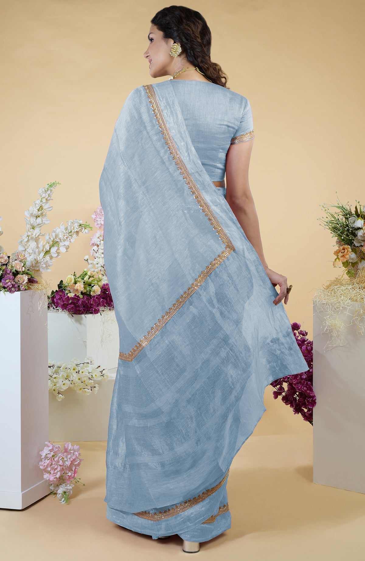 Dusty blue linen saree with hand-embroidered gold zardozi border and matching blouse.