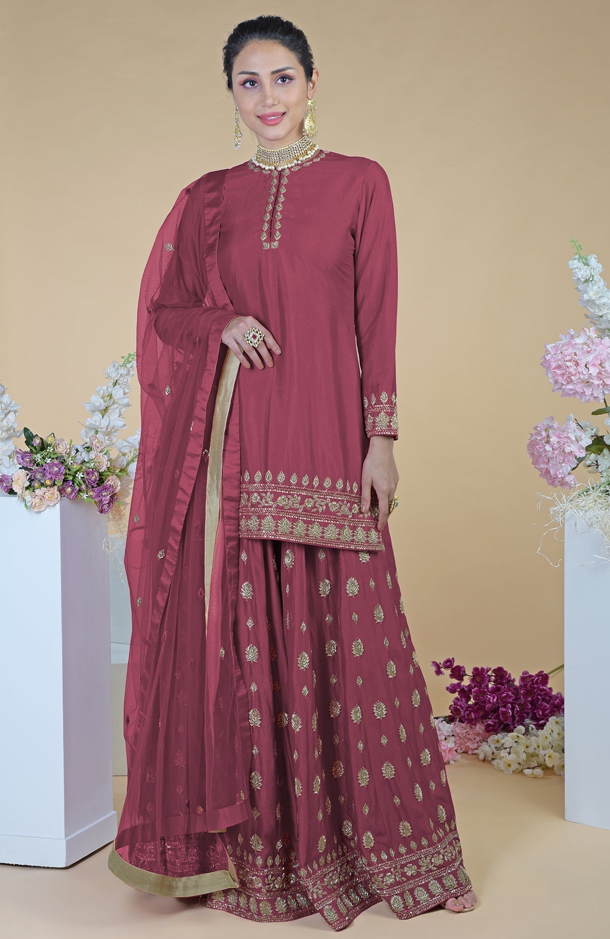 A woman models a crimson-gold zardozi dabka hand-embroidered sharara set.