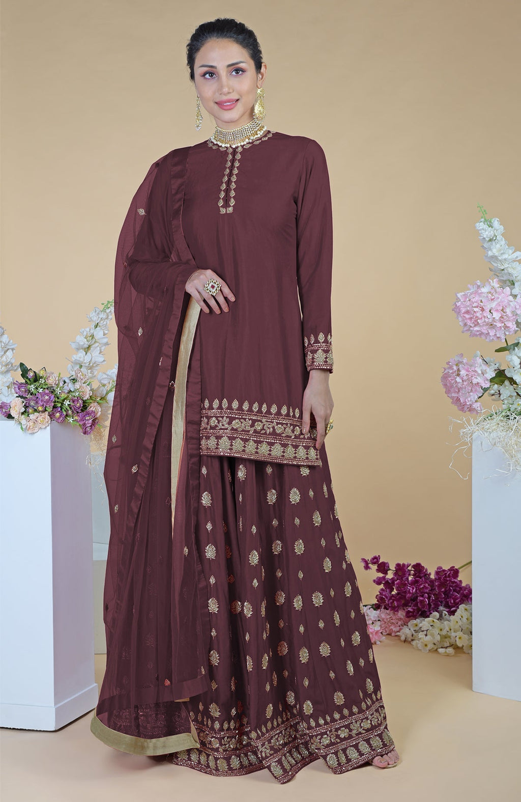 A woman models a midnight blue sharara set with gold embroidery and a sheer dupatta.