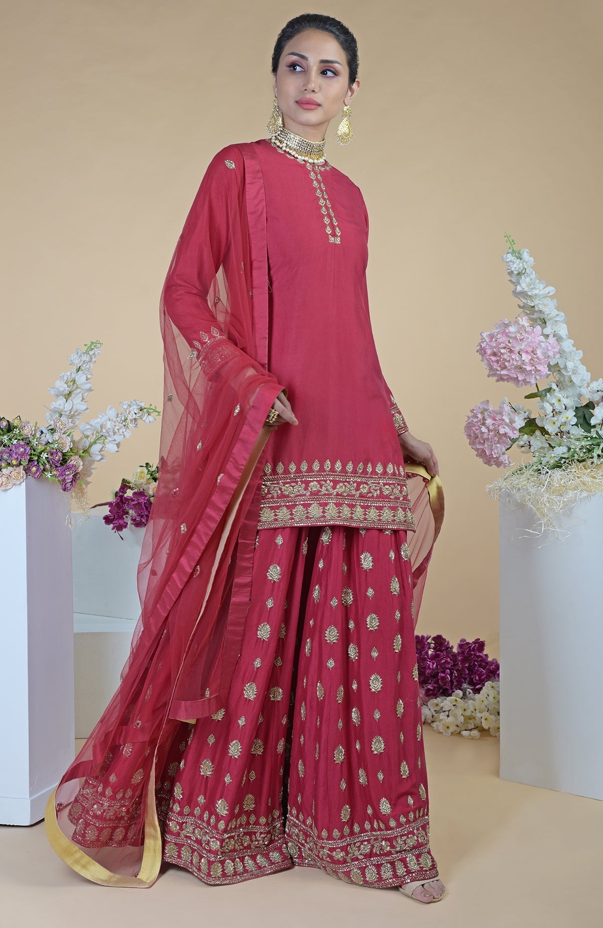 A woman models a crimson-gold zardozi dabka hand-embroidered sharara set.