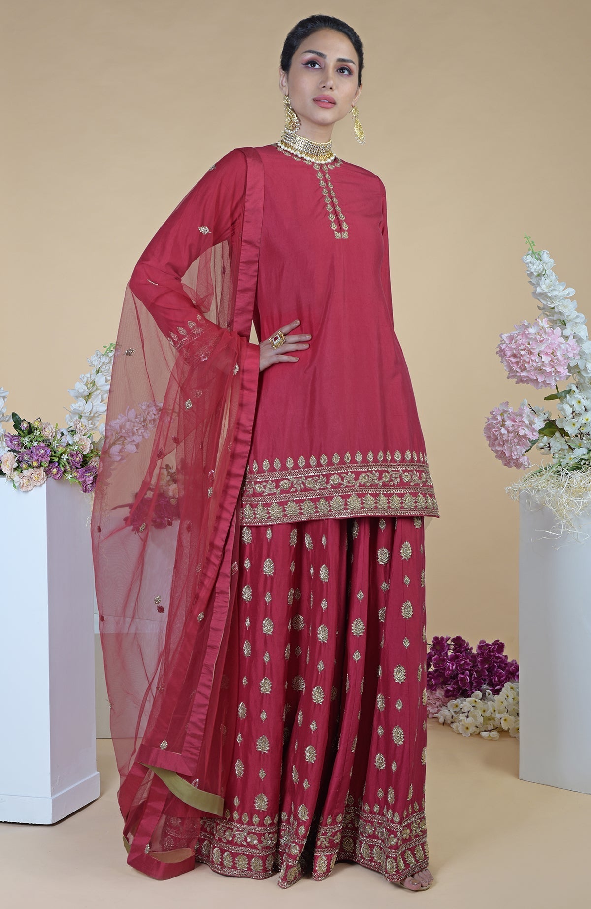 A woman models a crimson-gold zardozi dabka hand-embroidered sharara set.