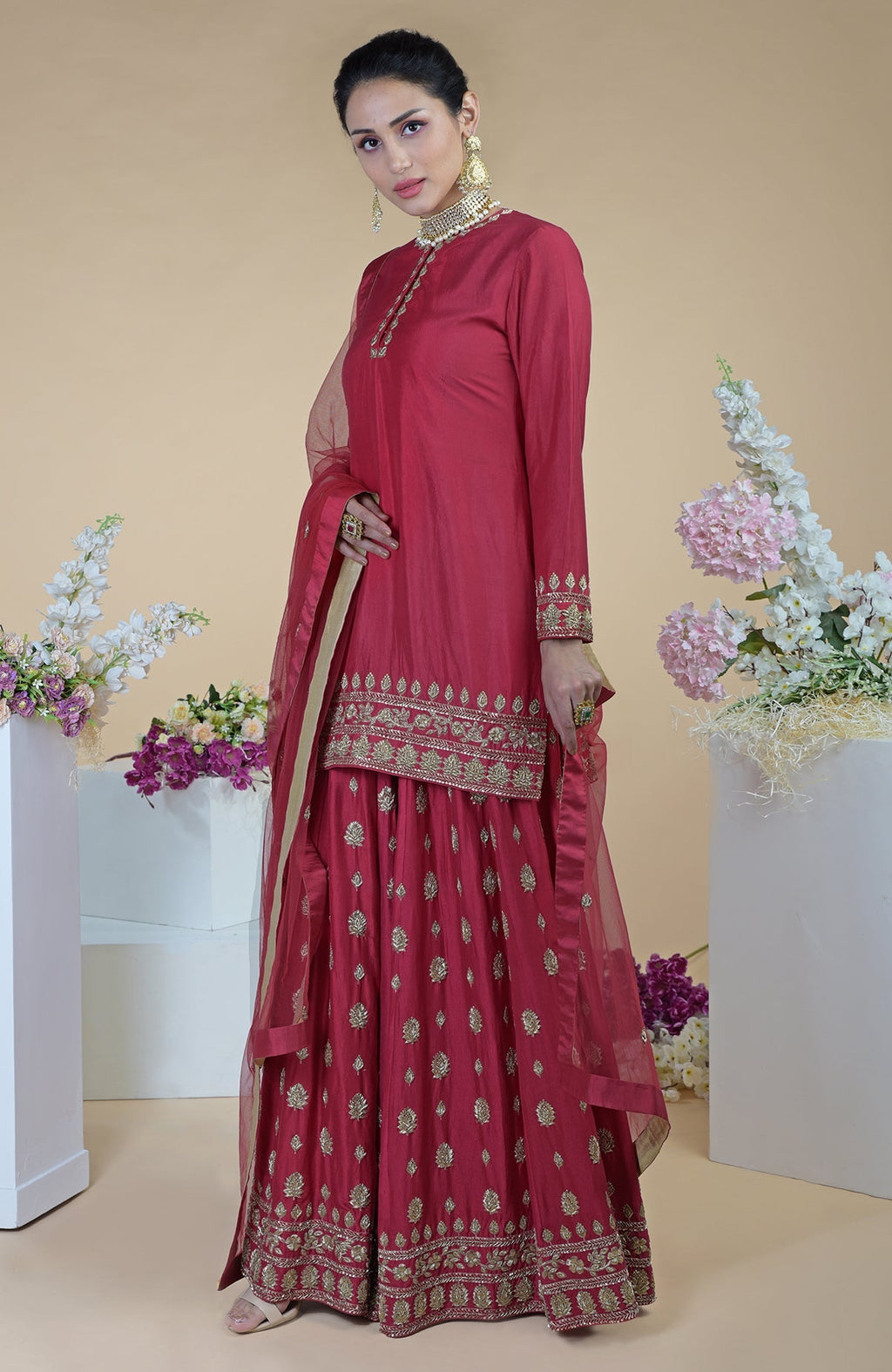 A woman models a crimson-gold zardozi dabka hand-embroidered sharara set.