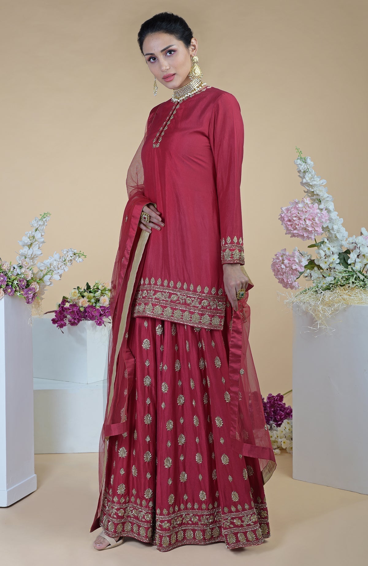 A woman models a crimson-gold zardozi dabka hand-embroidered sharara set.