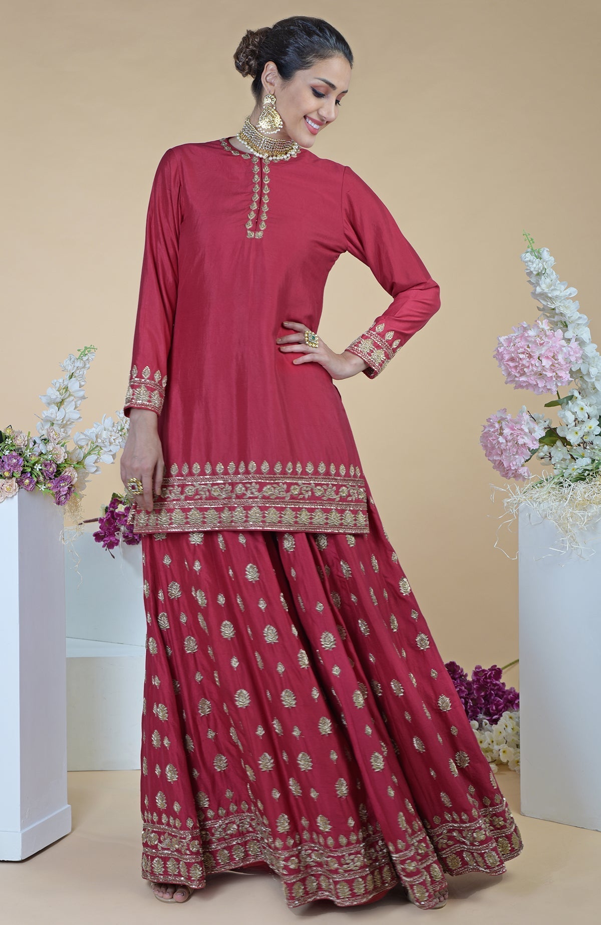 A woman models a crimson-gold zardozi dabka hand-embroidered sharara set.