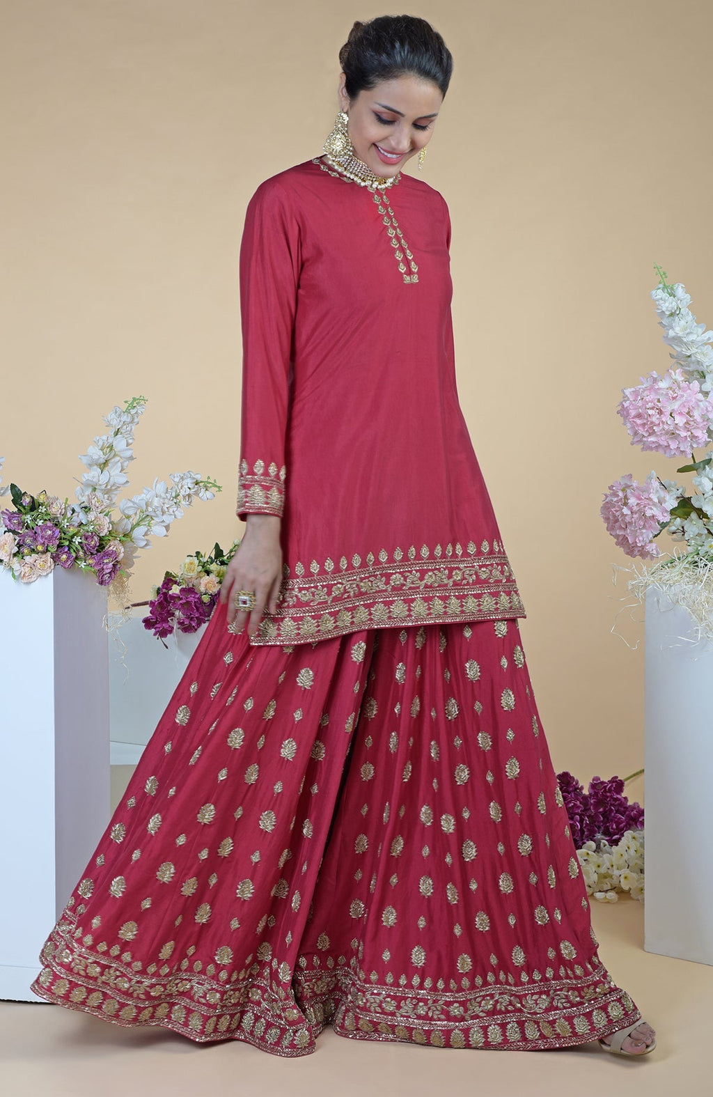 A woman models a crimson-gold zardozi dabka hand-embroidered sharara set.