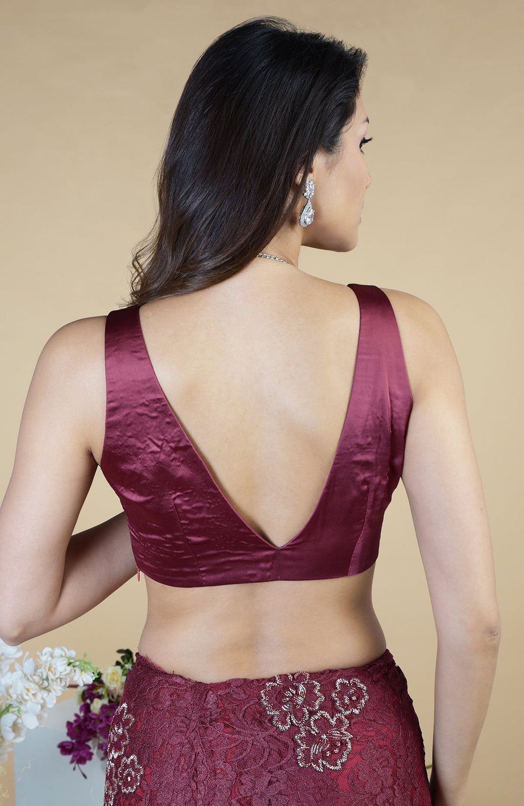 A woman models a burgundy French Chantilly hand-embroidered saree and matching blouse from the back.