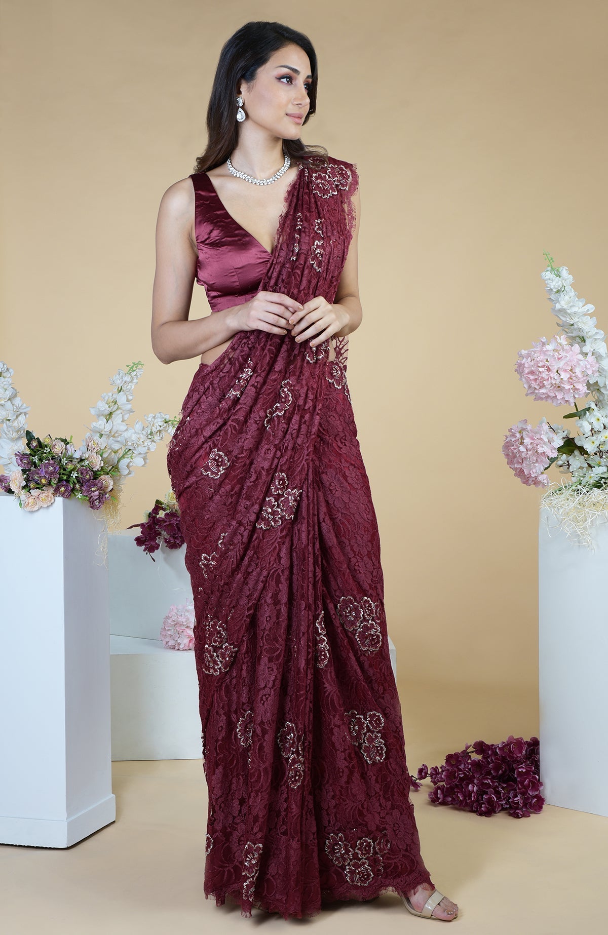 A woman models a burgundy French Chantilly hand-embroidered saree with a matching blouse.
