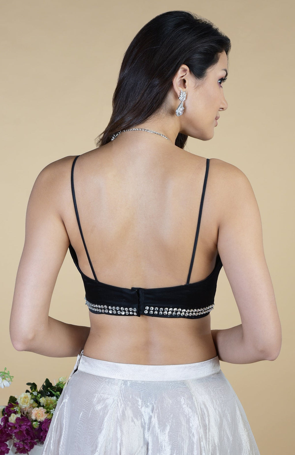 Rear view of a woman in a black embellished blouse and white skirt.