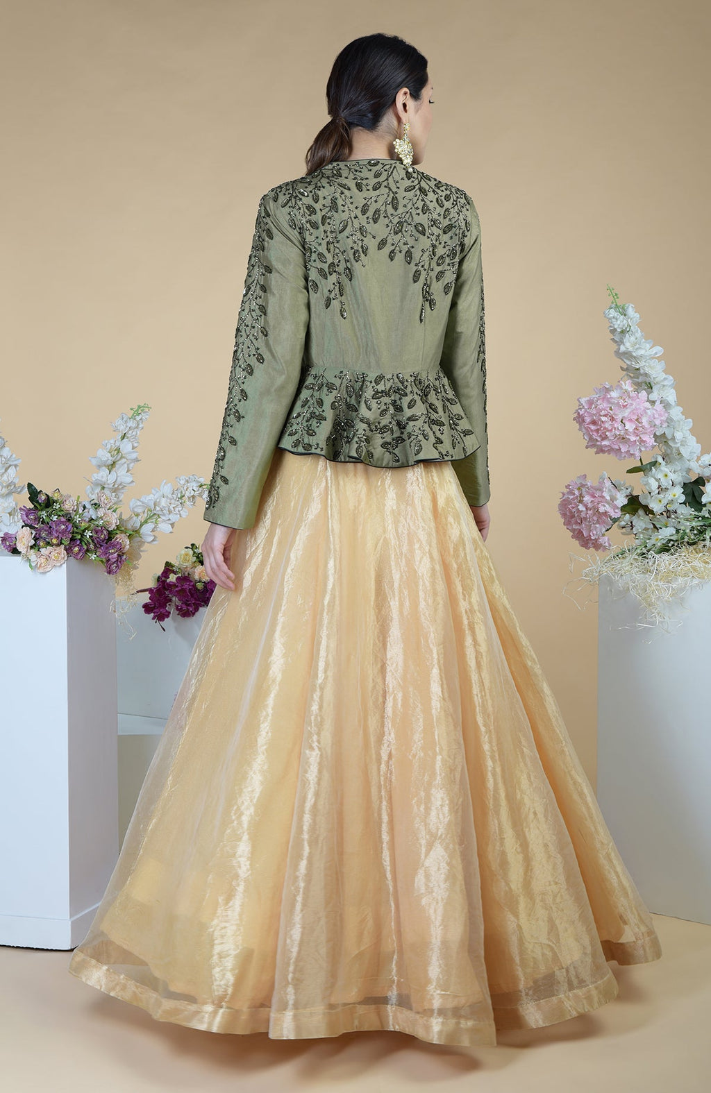 A woman from behind wears a dark foliage hand-embroidered peplum and skirt set.