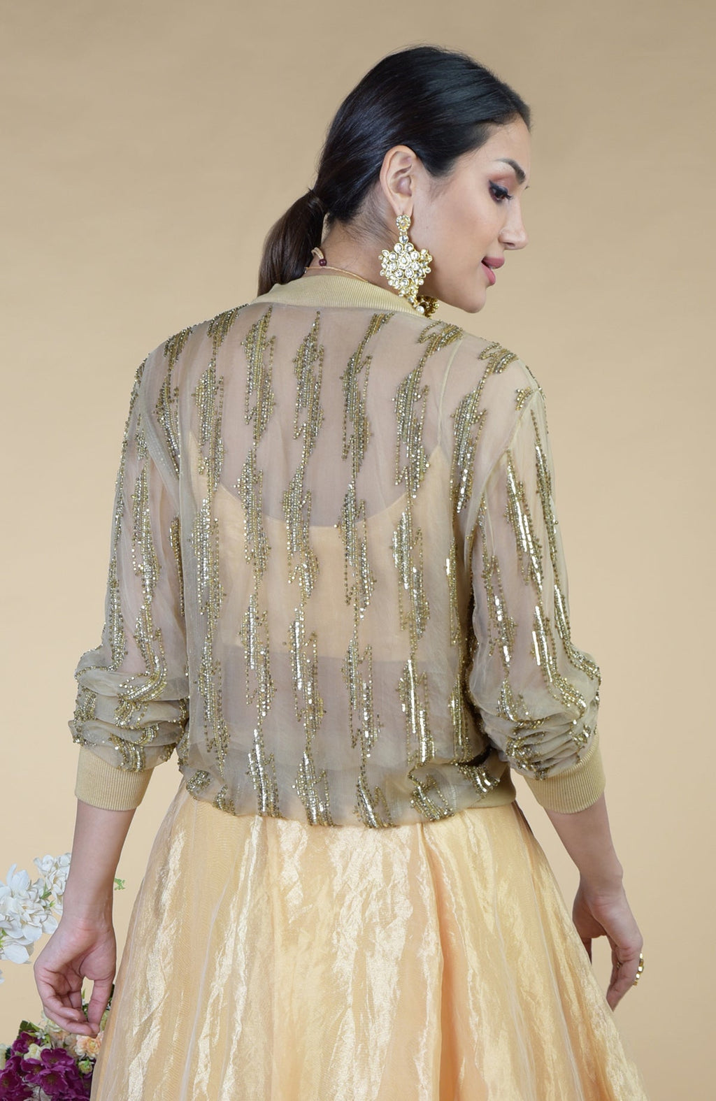 A woman models a sheer gold sequined cape over a matching skirt.