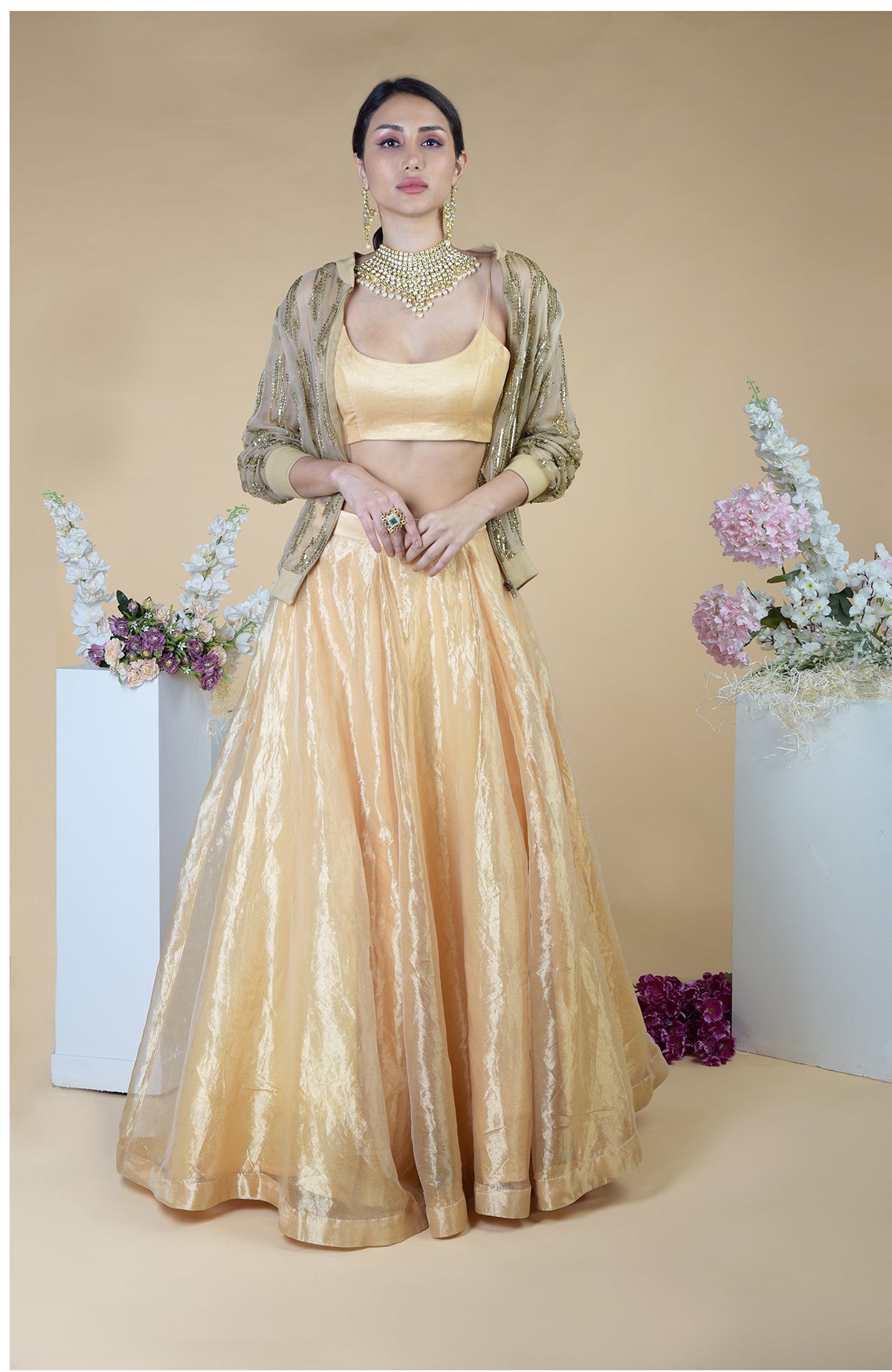 A woman models a gold hand-embroidered cape and skirt set.