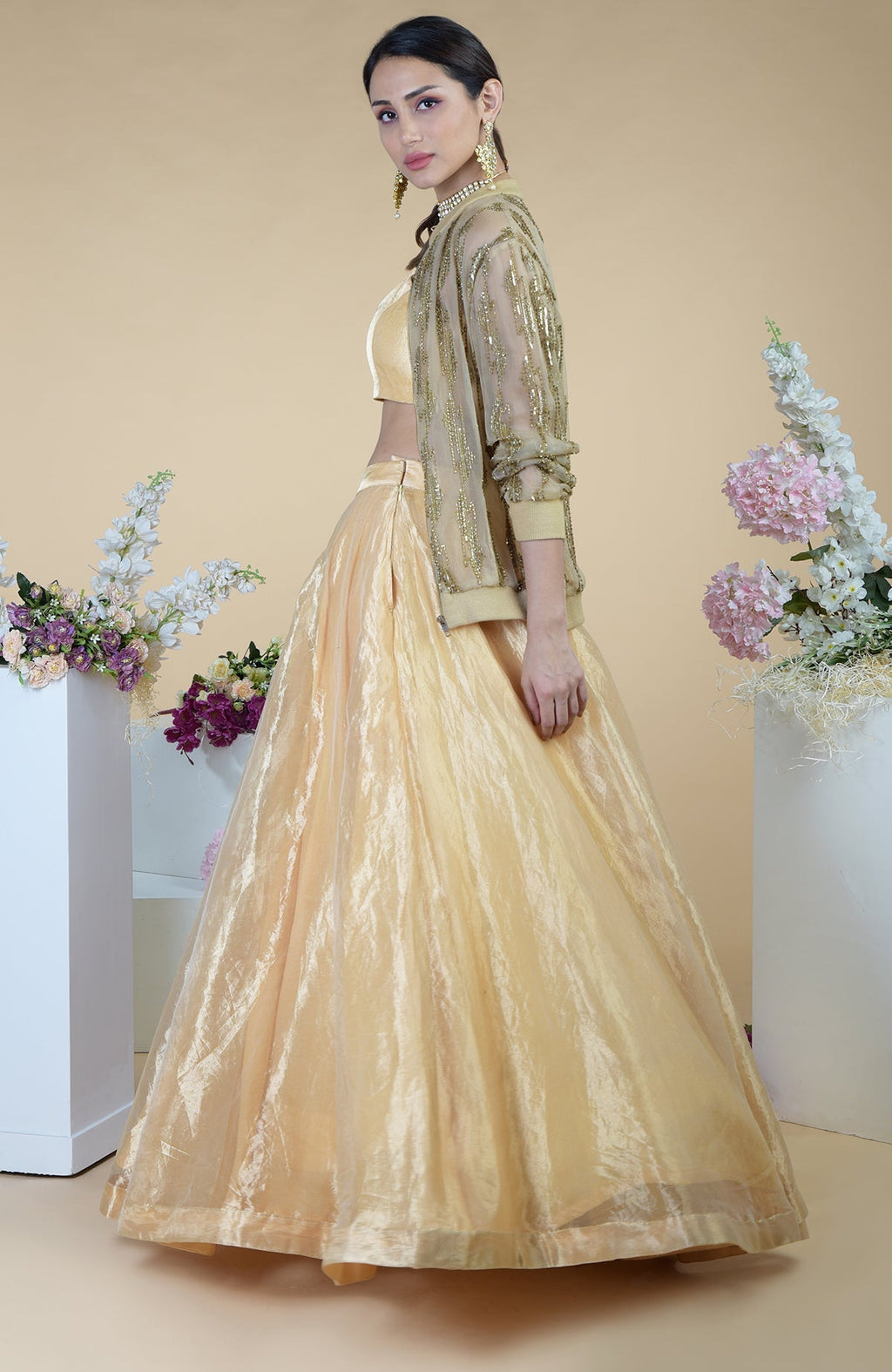 A woman models a gold organza jacket with a matching skirt and blouse.