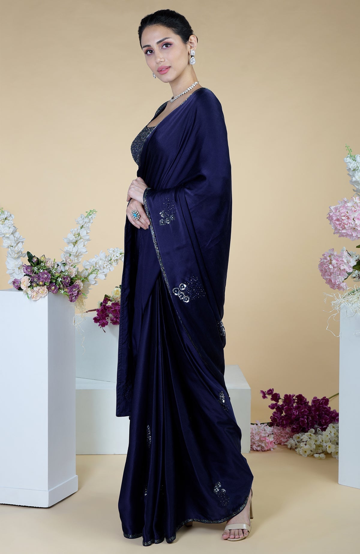 A woman models a midnight blue satin silk saree with bead and sequin embroidery.