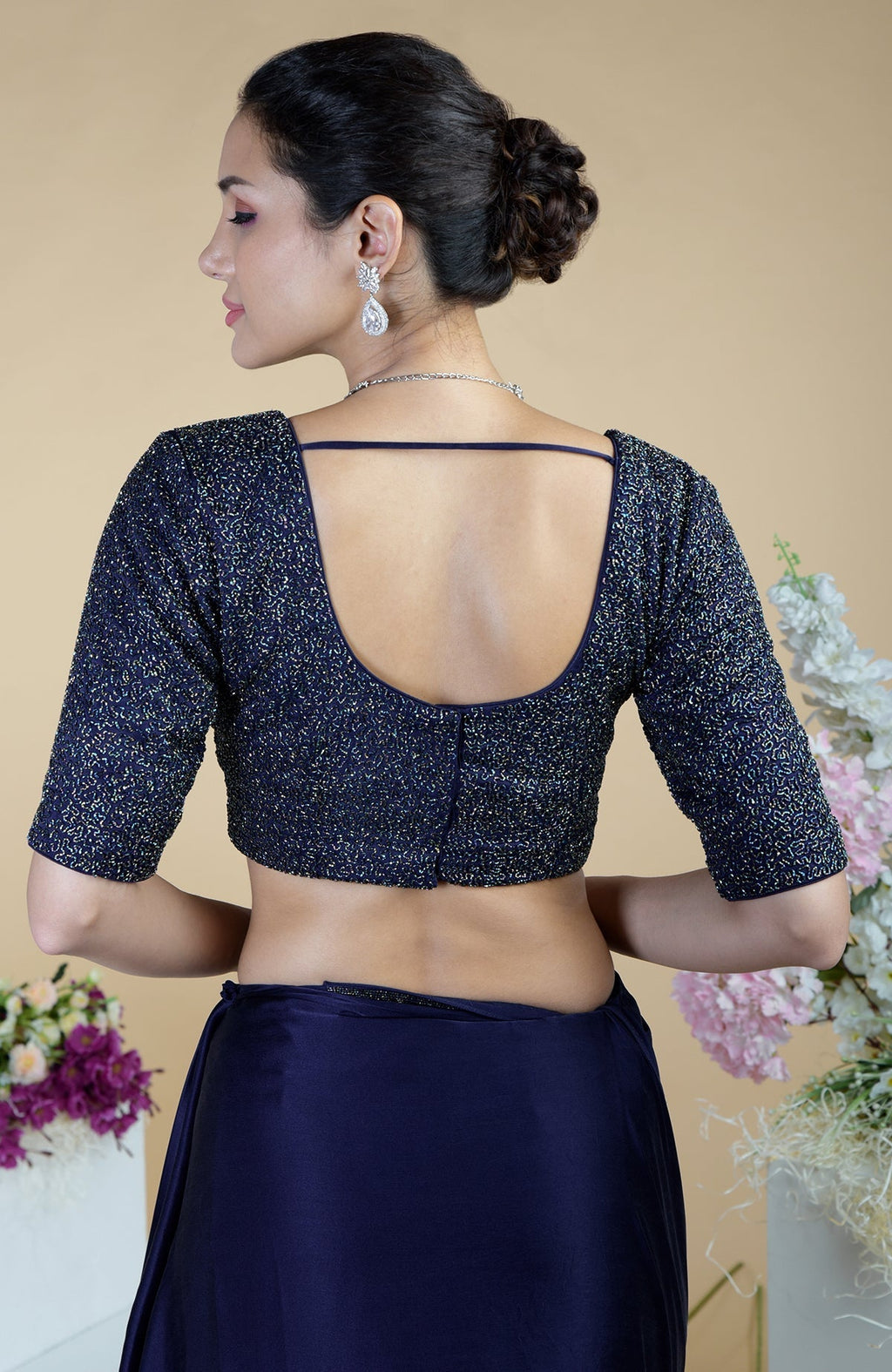 A woman models a midnight blue beaded and sequined saree and blouse from the back.
