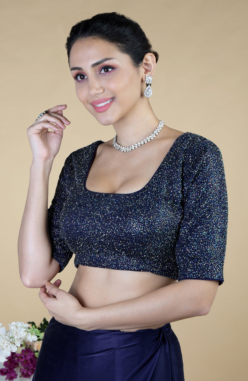 Woman in a midnight blue sequin blouse and matching saree with a diamond necklace.