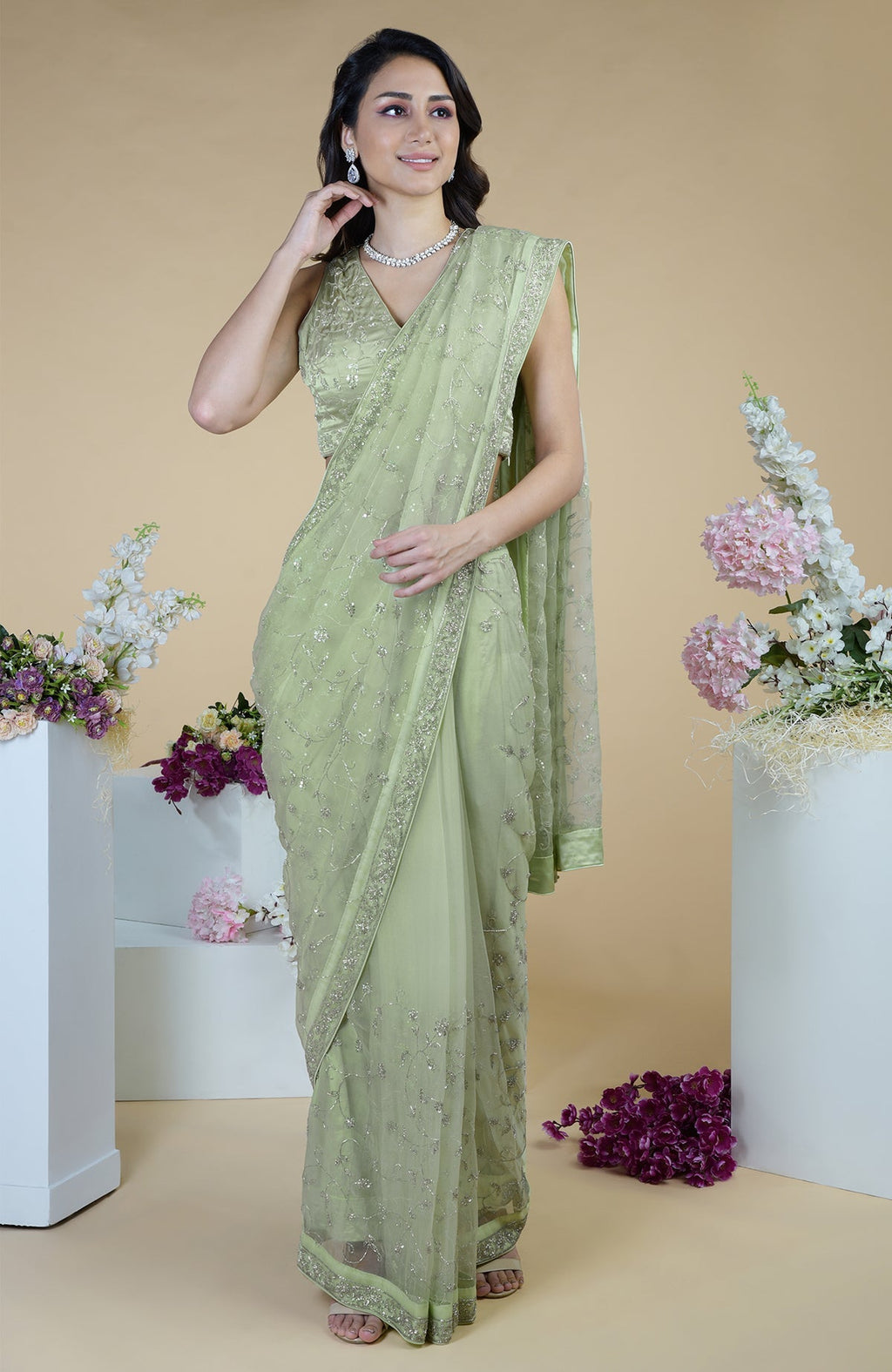 A woman models a pastel mint saree with silver beads and sequin zardozi hand embroidery.