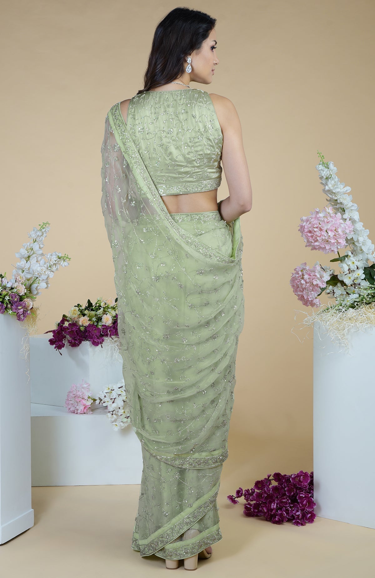 A woman models a pastel mint saree with silver beads and sequin embroidery.