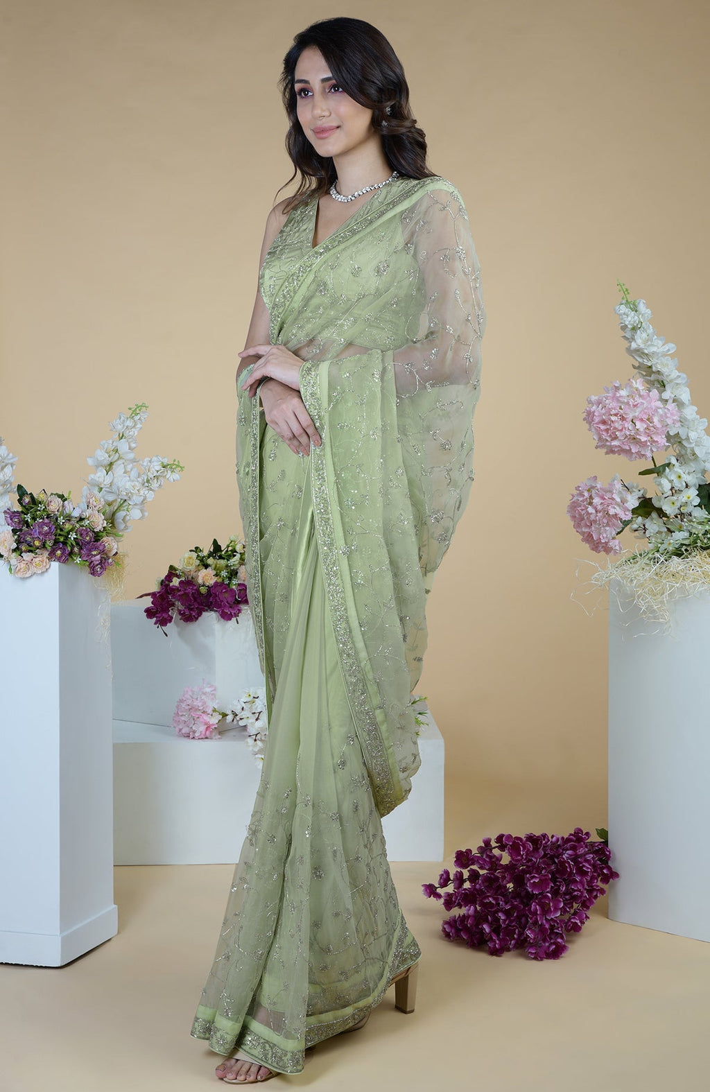 A woman models a pastel mint saree with silver beads and sequin zardozi embroidery.