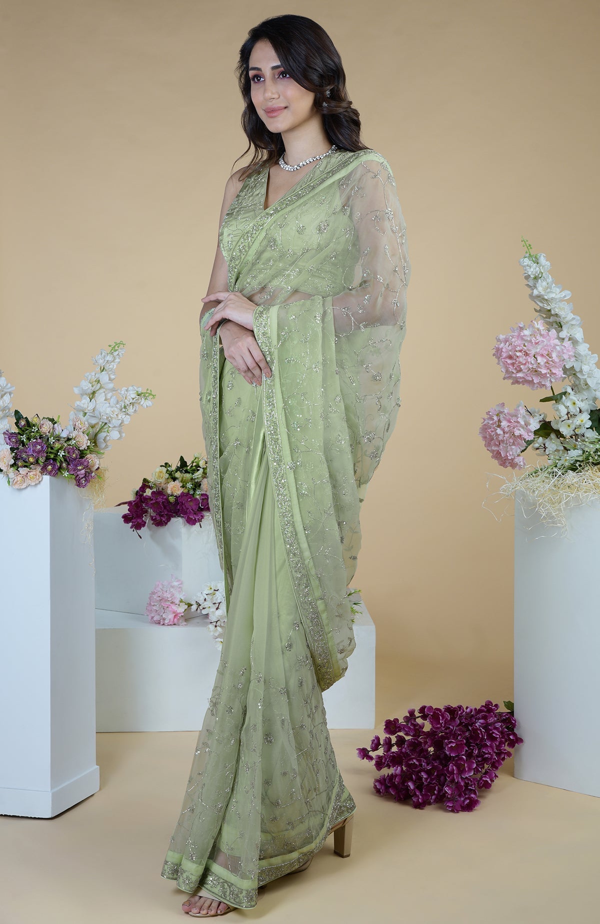 A woman models a pastel mint saree with silver beads and sequin zardozi embroidery.