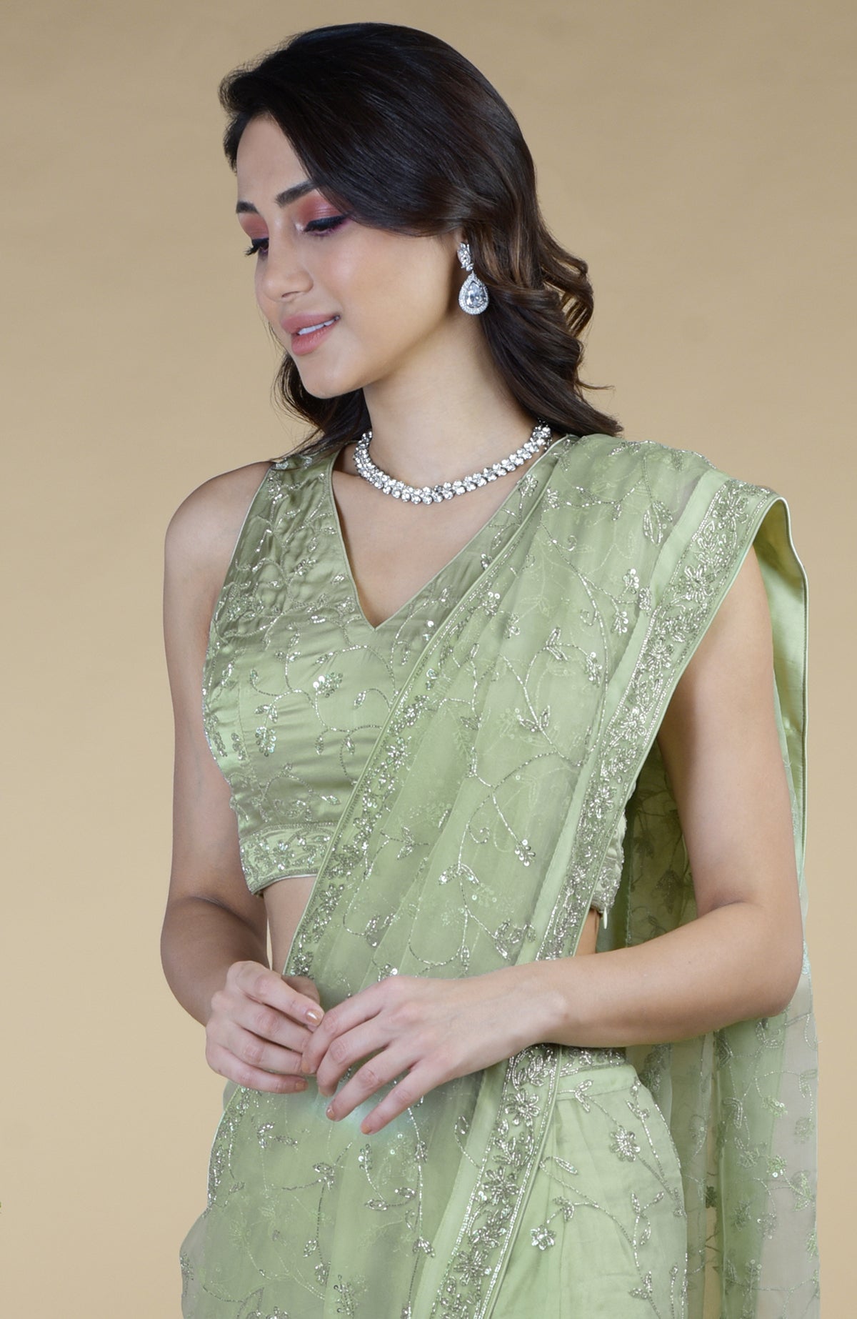 A woman models a pastel mint saree with silver beads and sequin zardozi hand embroidery.