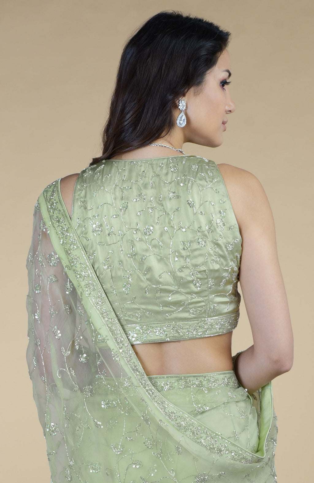 A woman models a pastel mint saree with silver bead and sequin embroidery.