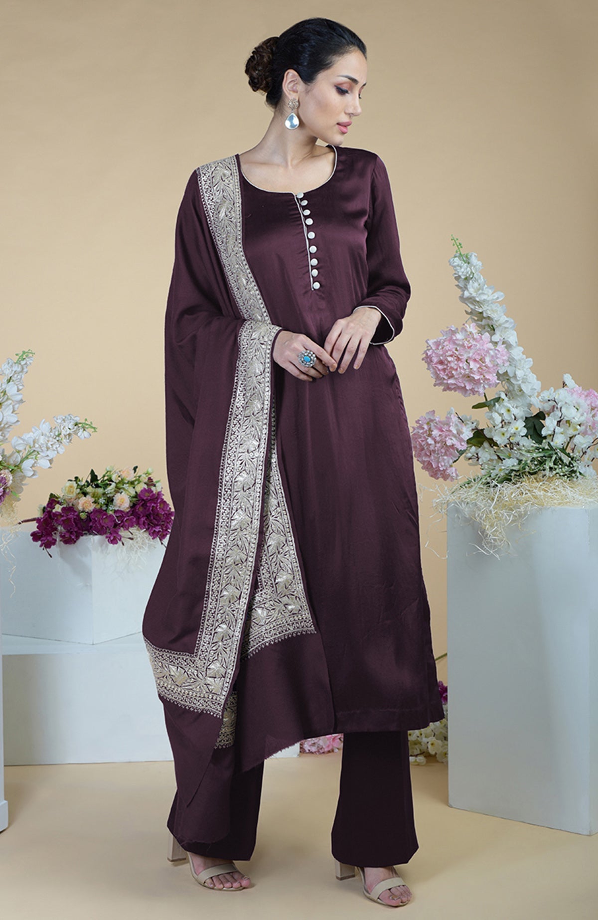 A woman models a dark teal silk suit with a silver embroidered dupatta.
