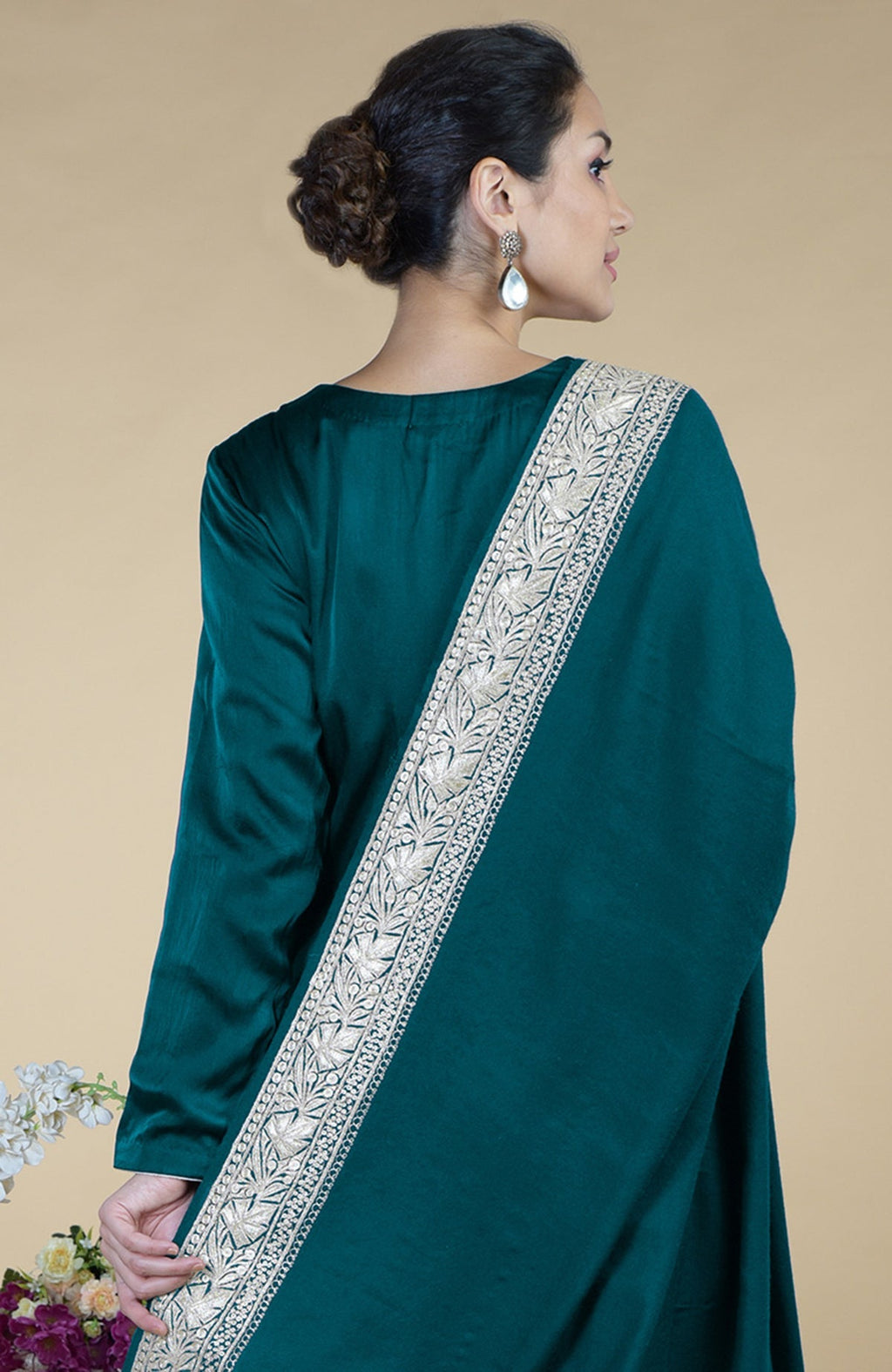 A woman models a teal silk suit with a silver embroidered dupatta.