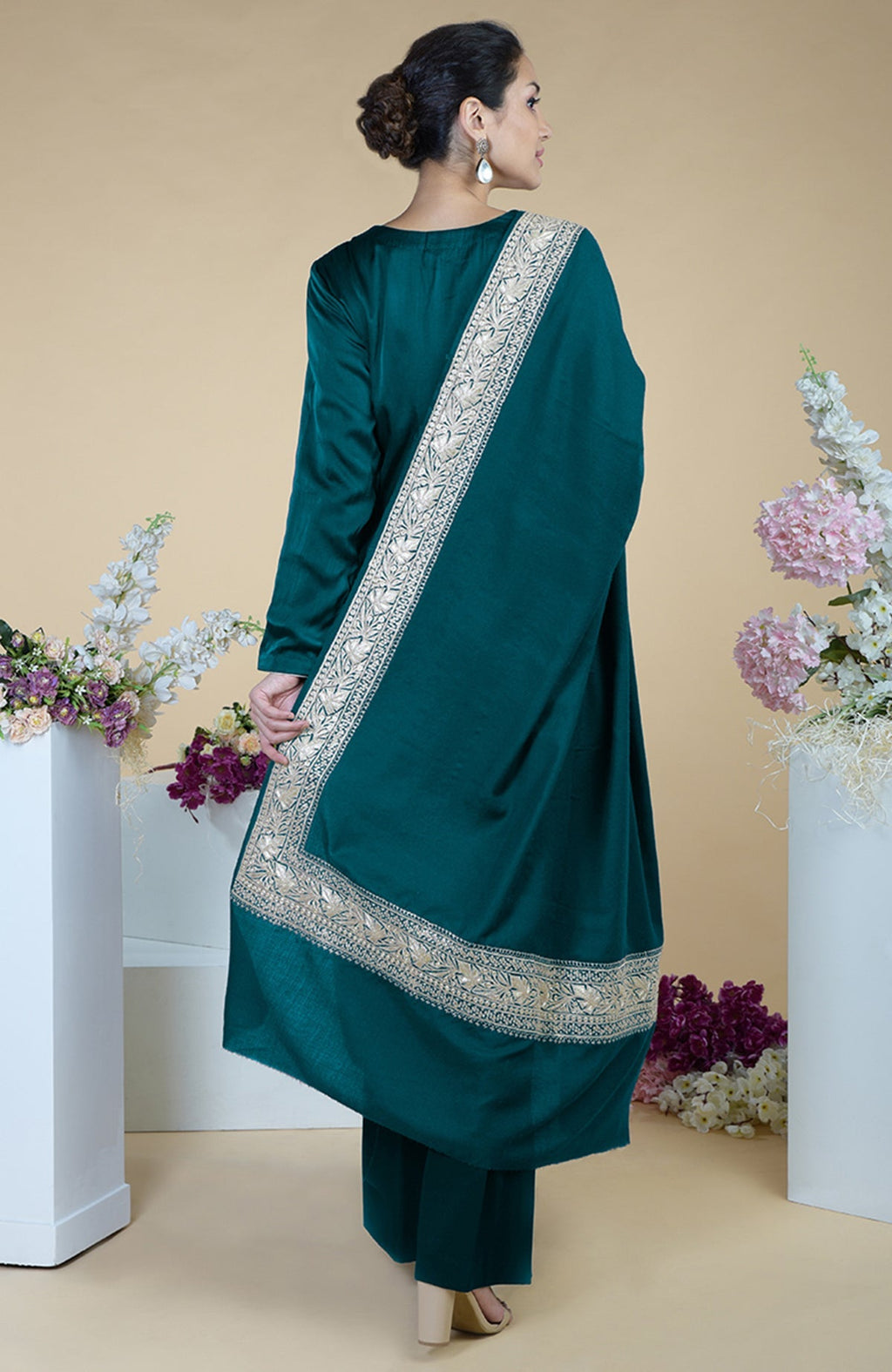 A woman in a teal silk suit with a tilla embroidered dupatta draped over her shoulder.