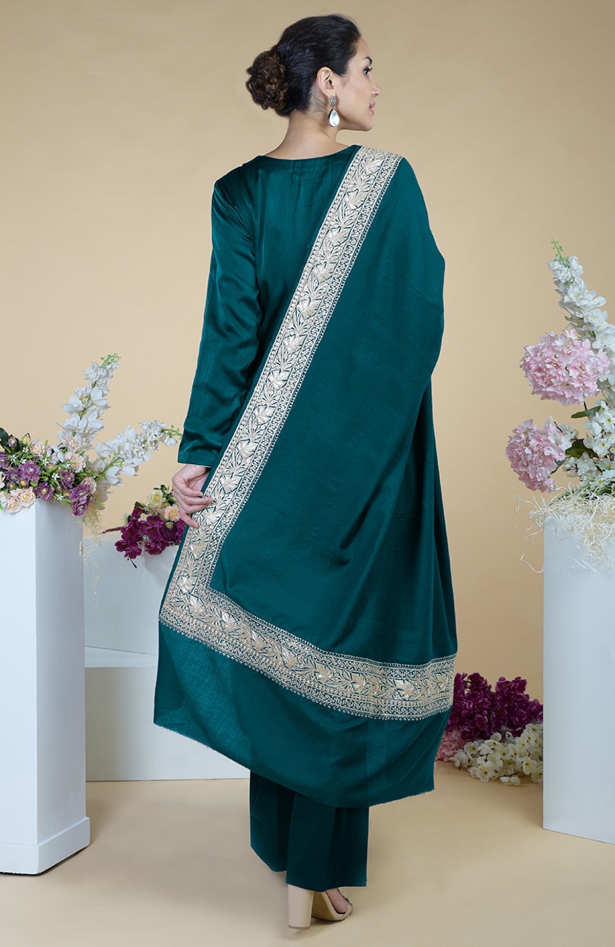 A woman in a teal silk suit with a tilla embroidered dupatta draped over her shoulder.