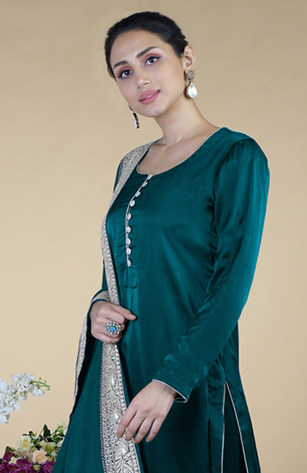 A woman models a teal silk suit with a silver embroidered dupatta and a turquoise ring.