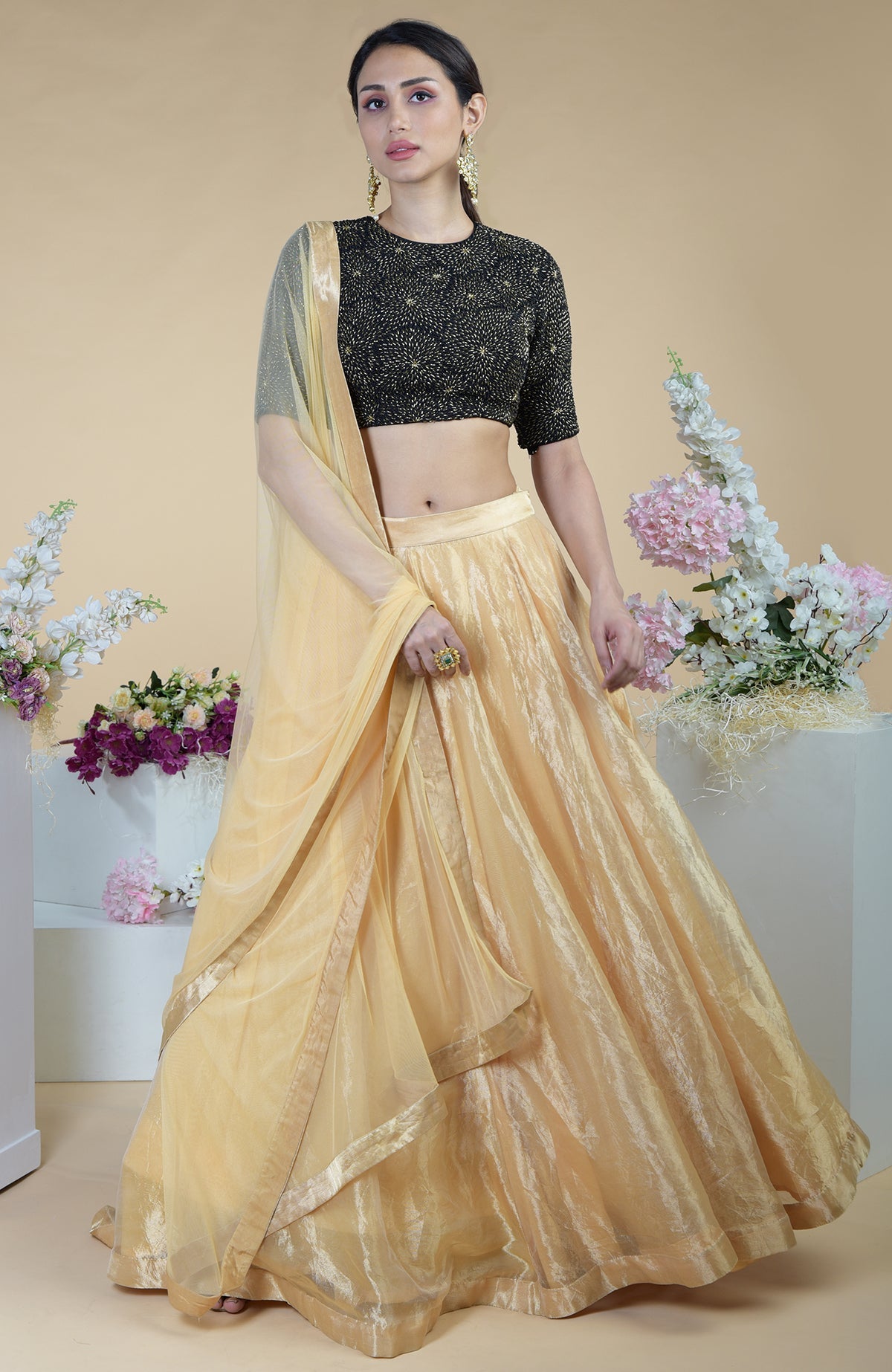 A woman models a black and gold hand-embroidered blouse with a gold tissue skirt.