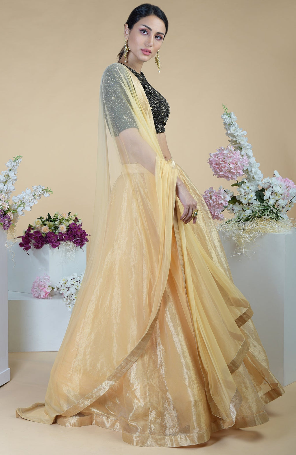 A woman models a black-gold hand-embroidered blouse with a gold tissue skirt.