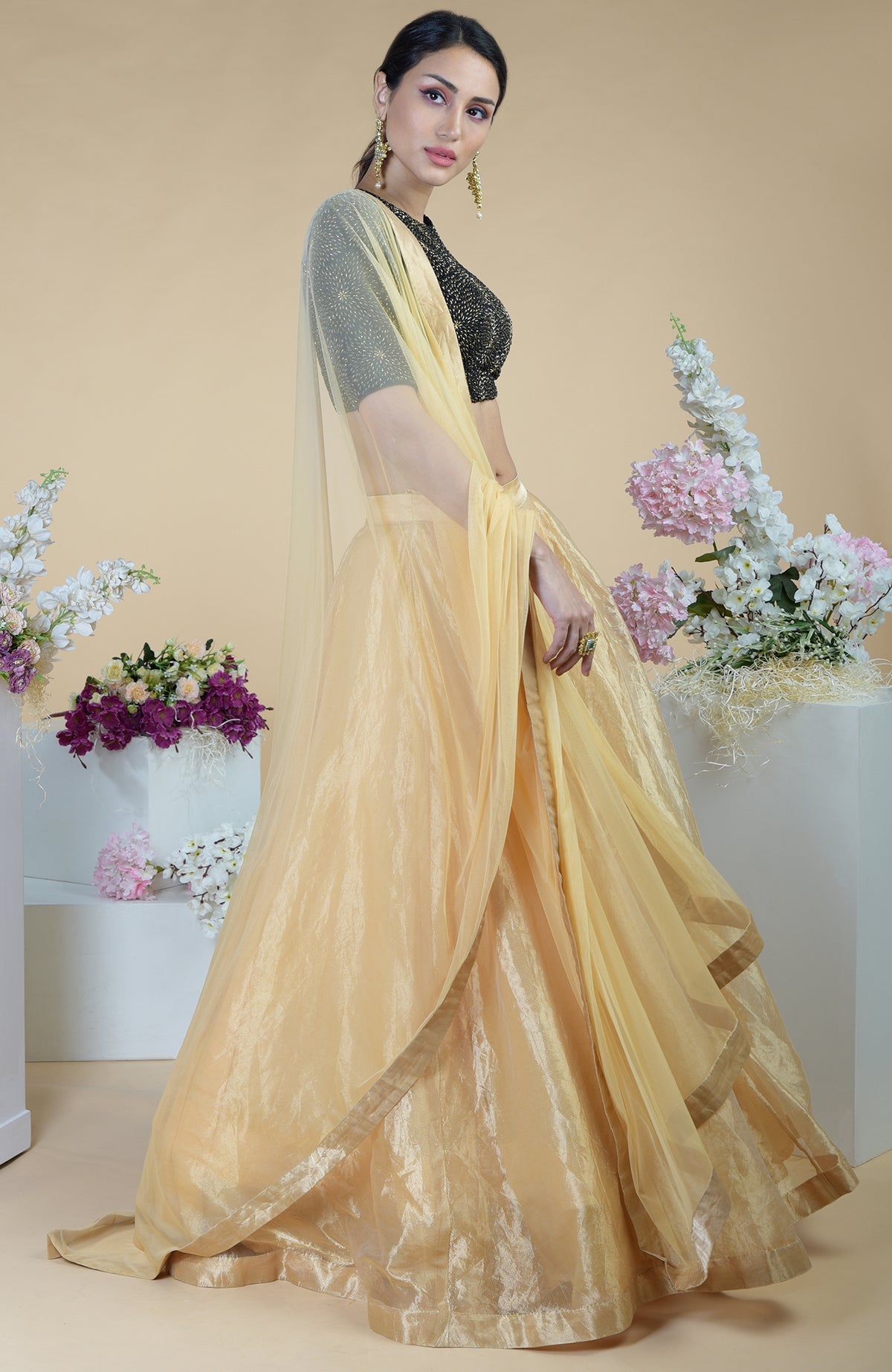 A woman models a black-gold hand-embroidered blouse with a gold tissue skirt.