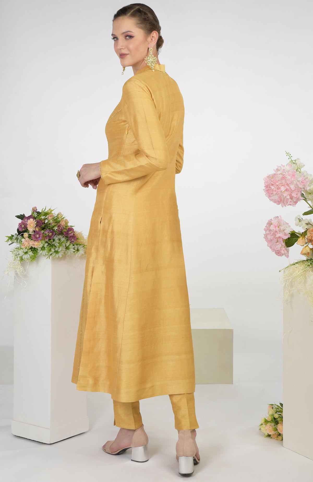 A woman models a gold raw silk kurta set with hand embroidery.