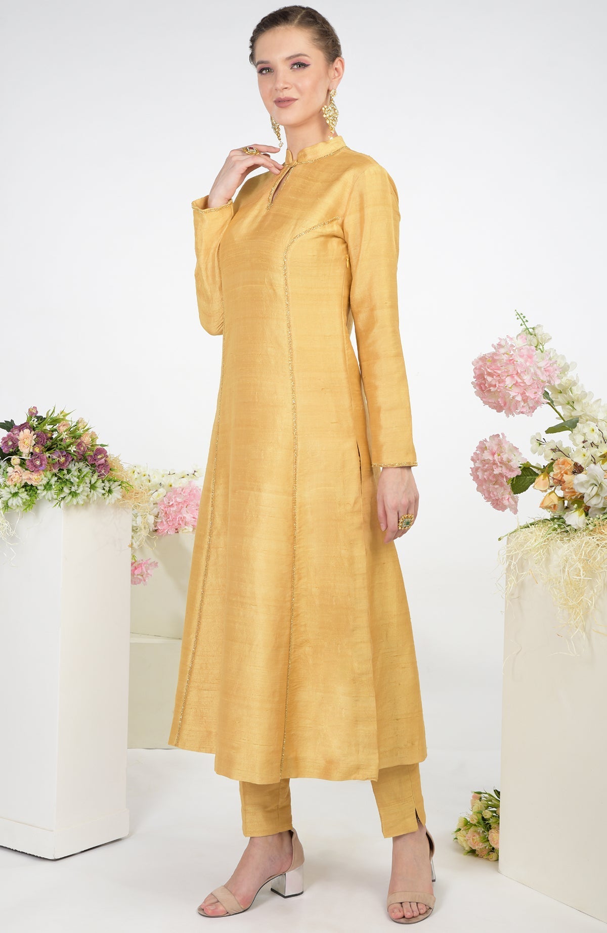 A woman models a gold raw silk kurta set with hand embroidery.