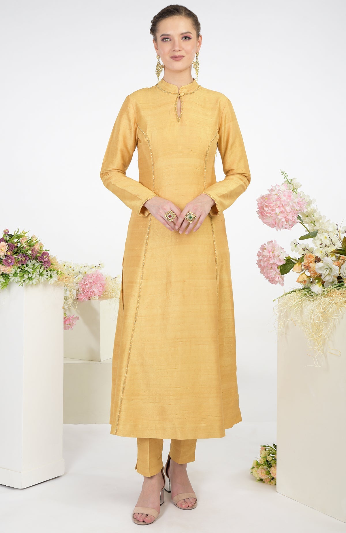 A woman models a gold raw silk kurta set with zardozi hand embroidery.