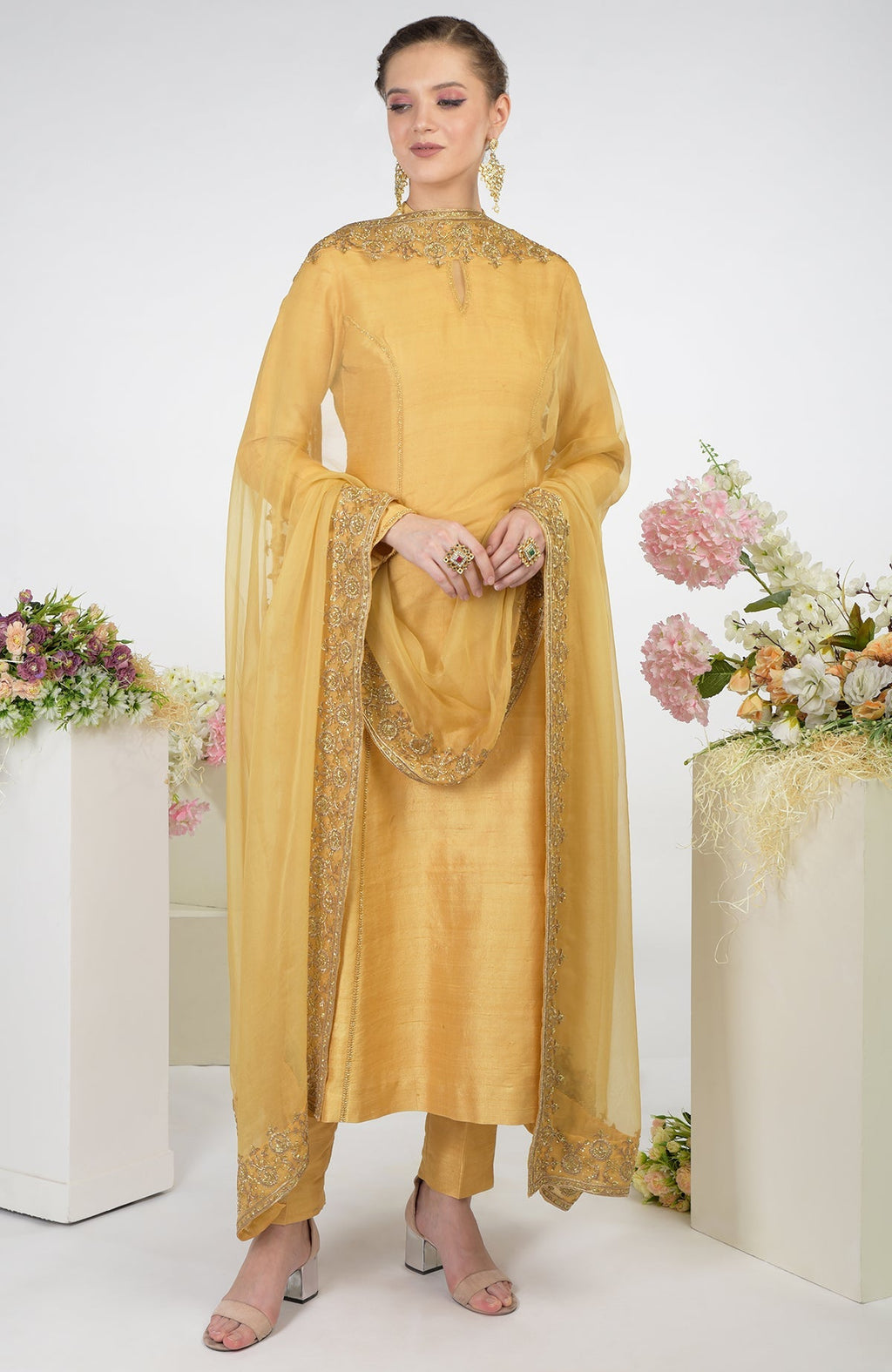 A woman models a gold hand-embroidered raw silk kurta set with an organza dupatta.