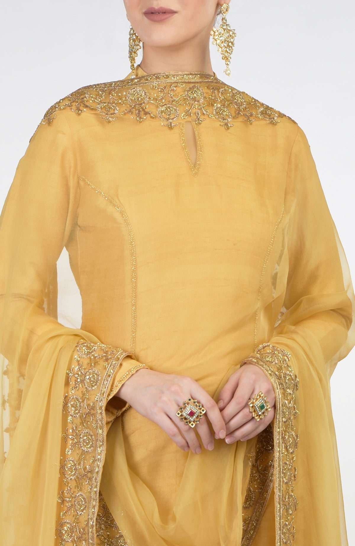 A woman models a gold hand-embroidered organza dupatta with a raw silk kurta set.