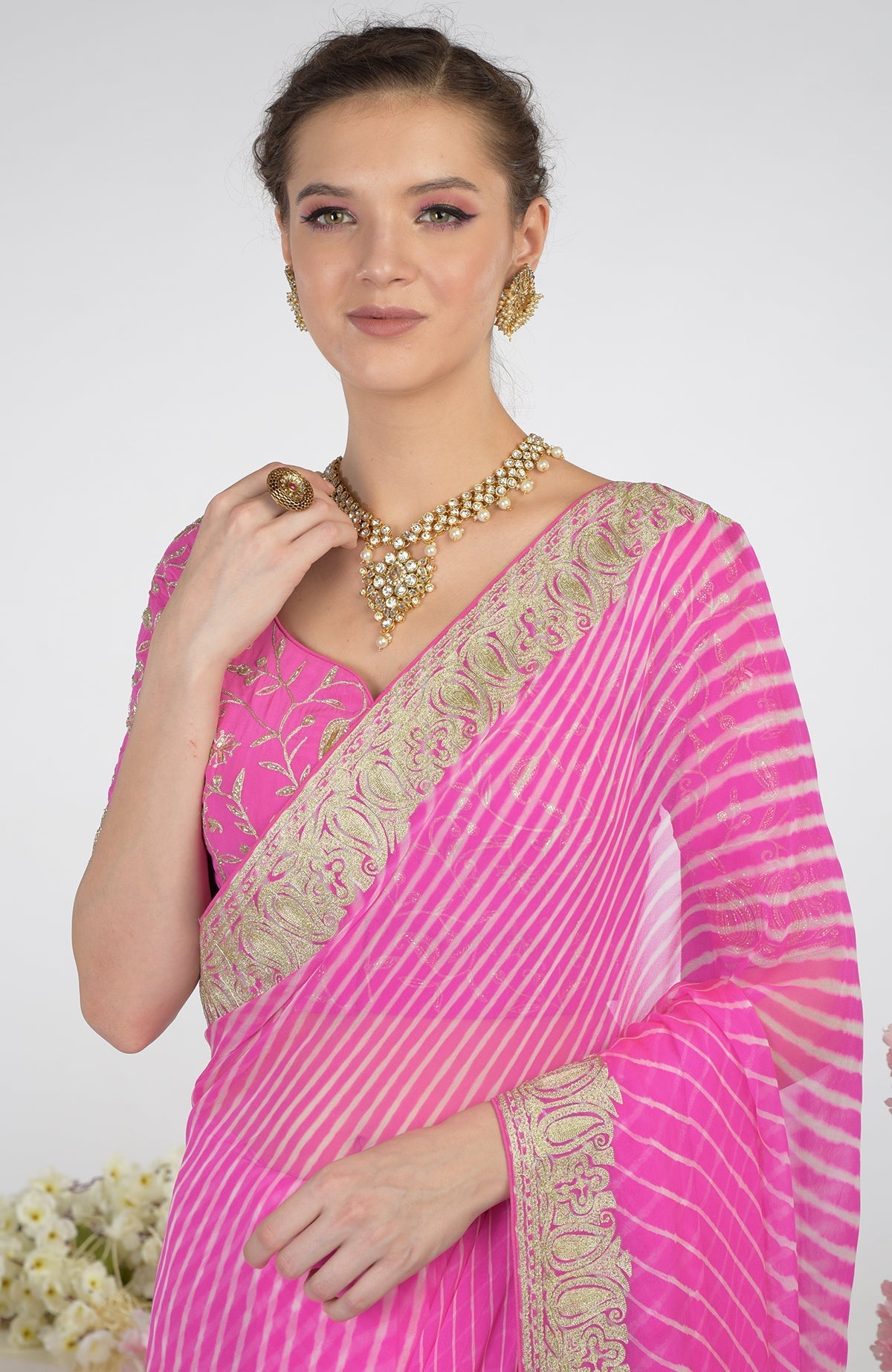 A woman models a pink leheriya saree with Kashmiri paisley tilla aari embroidery.