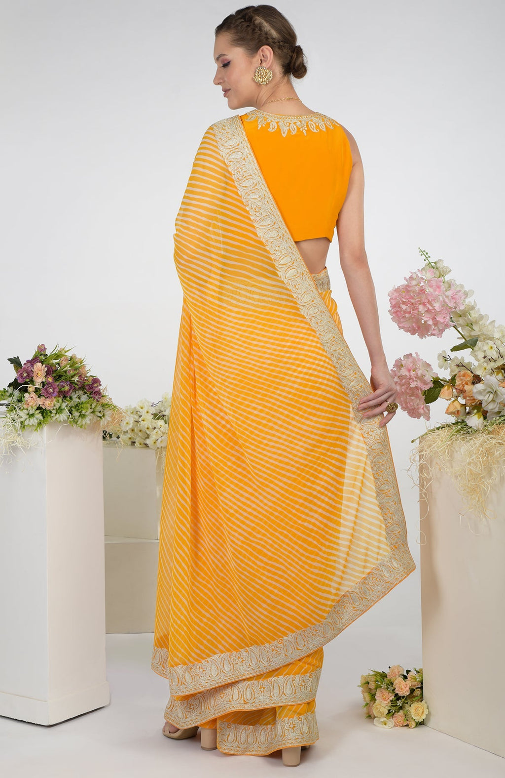 A woman models a yellow leheriya saree with Kashmiri paisley tilla aari embroidery.