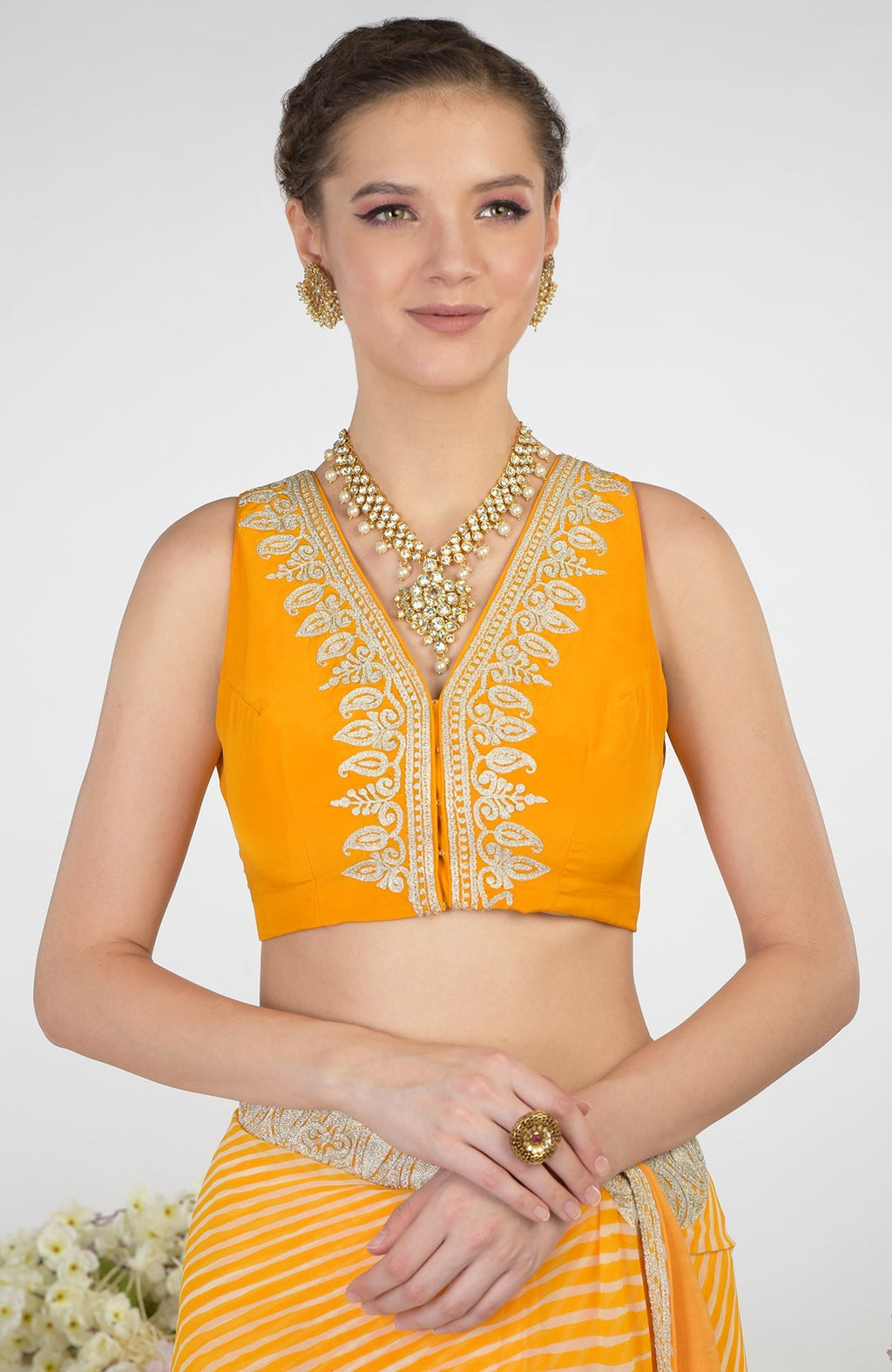 Woman in a yellow leheriya saree with a matching embroidered blouse and jewelry.