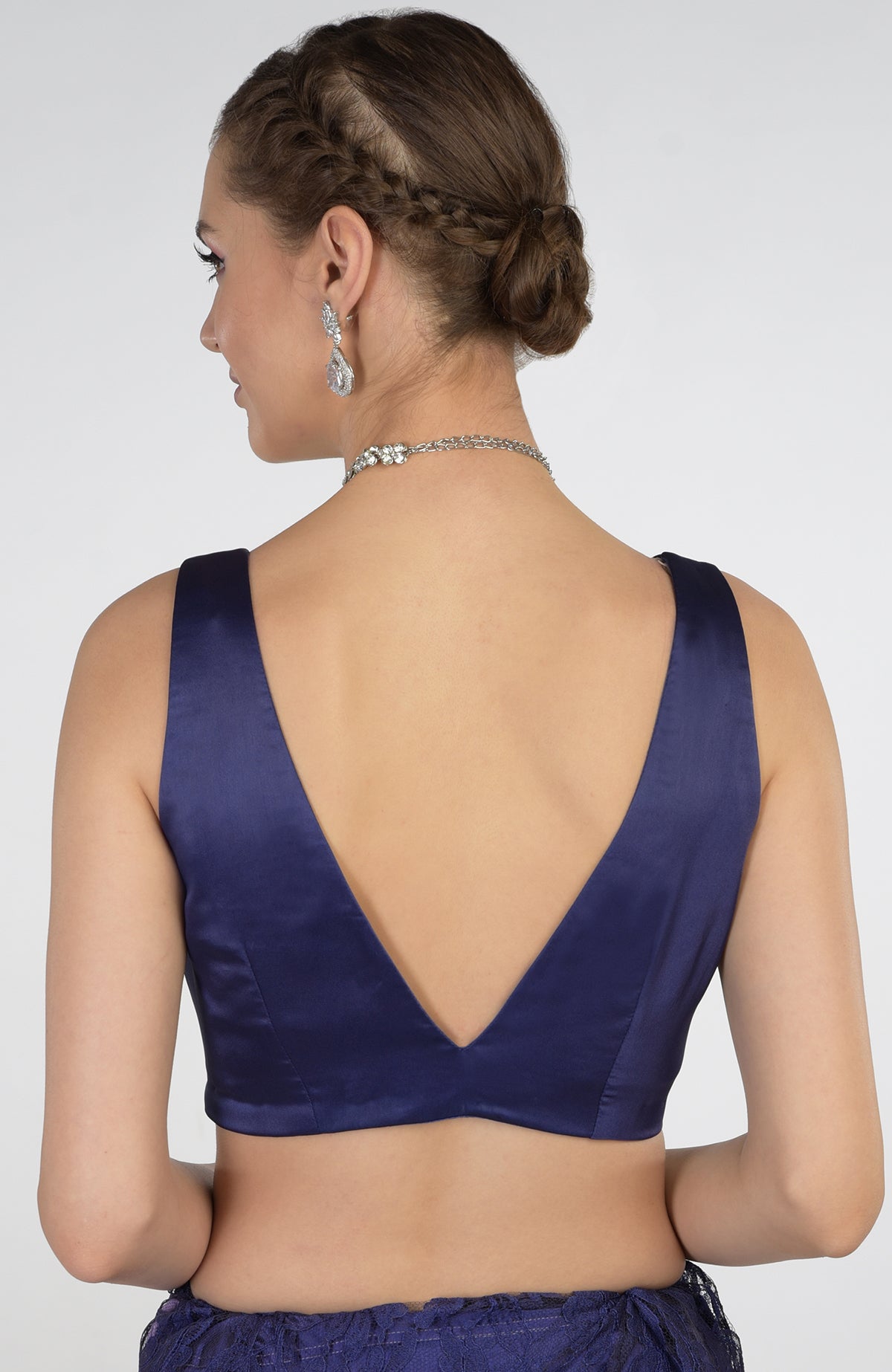 A woman from the back wearing a blue lace saree and a deep V-neck blouse.