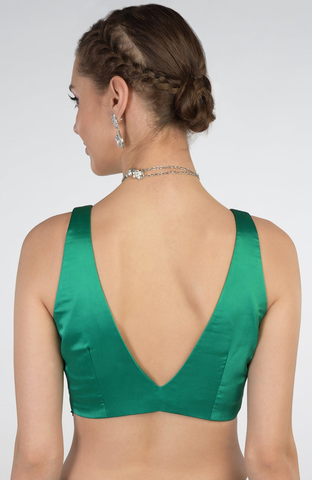 A woman from behind wearing an emerald green blouse with a deep V-neck back.