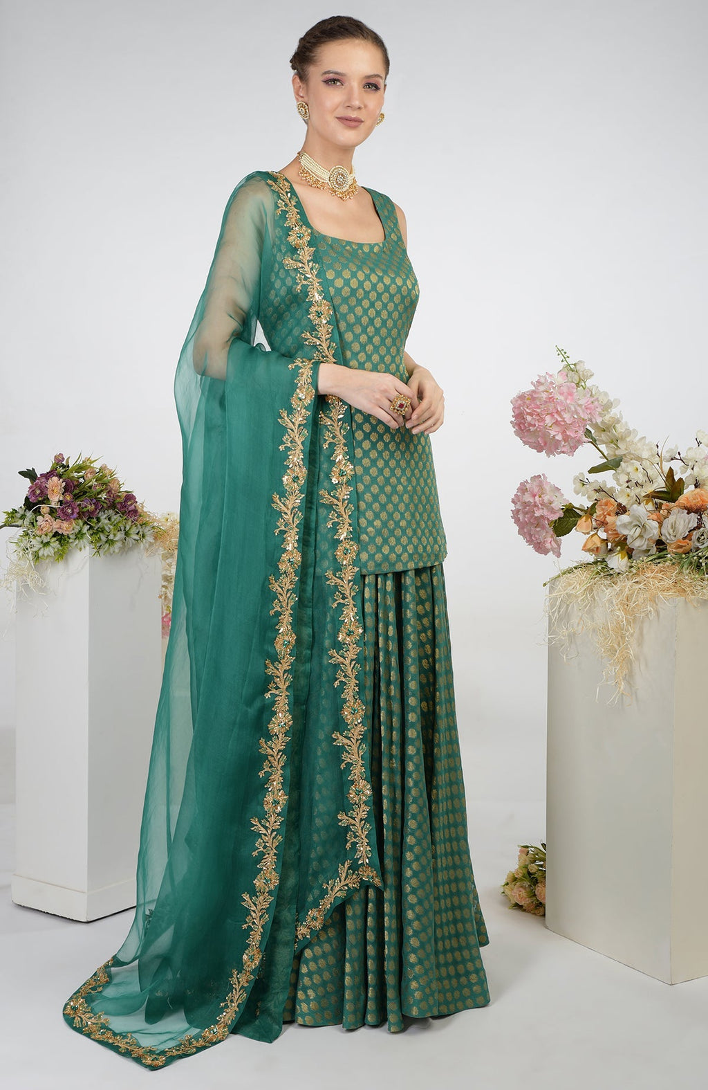 A woman models a bottle green Banarasi zardozi kalidaar skirt set with a short tunic.